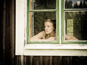 Portrait of woman looking through window