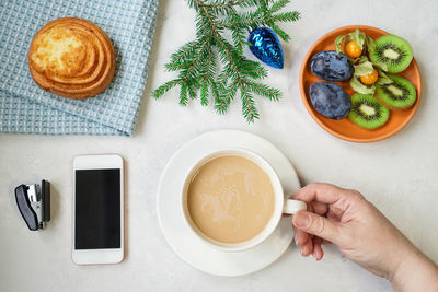 High angle view of woman holding coffee cup on table
