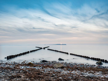 Crossed breakwater. ruegen island. morning mood at shore. hiddensee island with shinning lighthouse