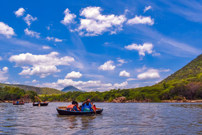 People on boat in sea against sky