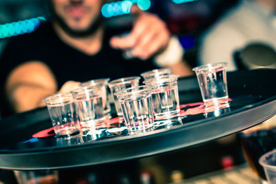 Tilt shot of bartender offering drinks on tray at bar