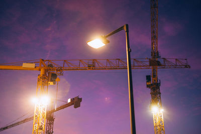 Low angle view of illuminated crane against sky