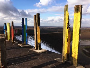 Wooden posts in sea against sky