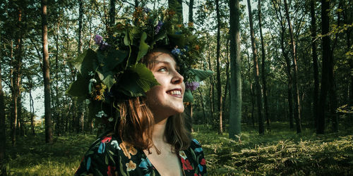 Smiling young woman wearing tiara standing in forest