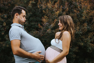 Young couple standing against trees