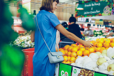 Woman standing by fruits for sale at market stall