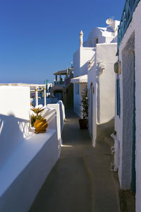 White umbrella on street amidst buildings against clear blue sky