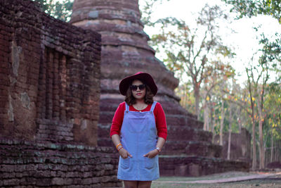 Young woman wearing hat and sunglasses against historic temple