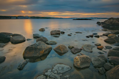 Rocks at sea shore against sky during sunset