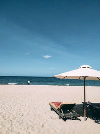 Deck chairs on beach against sky