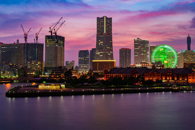 Illuminated buildings in city against sky at sunset