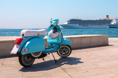 Blue scooter stands on the waterfront on the background of cruise ships in sunny weather. 