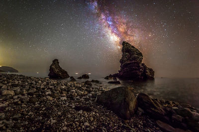 Rock formation in sea against sky at night