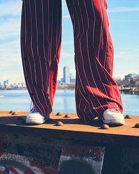 Low section of person on bridge over river against sky