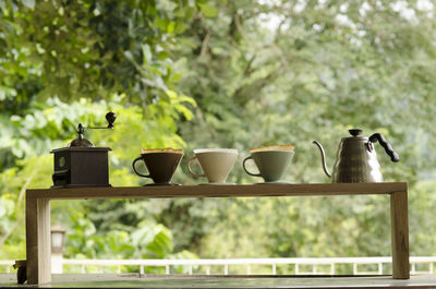 Low angle view of coffee cups on table against trees