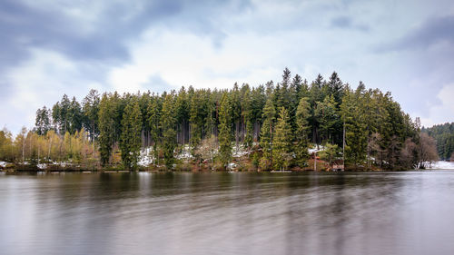 Scenic view of river by trees against sky