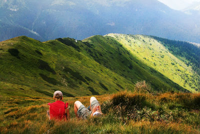 People sitting on landscape against mountain range