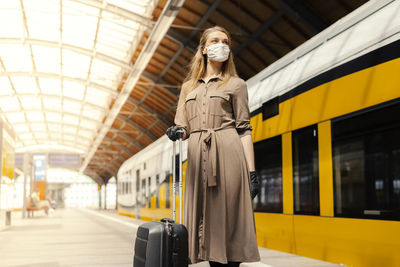 Low angle view of woman wearing mask standing at railroad station