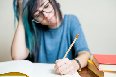 Young woman writing on book at desk