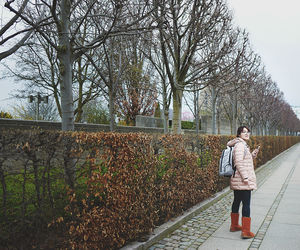 Rear view of boy standing by tree against sky