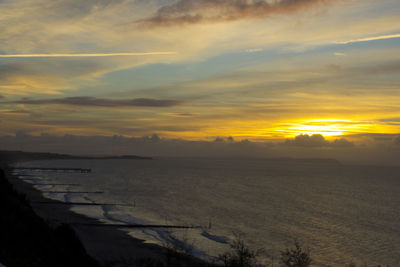 Scenic view of sea against cloudy sky during sunrise