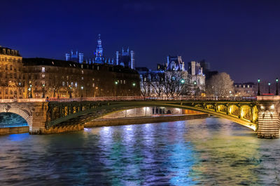 Illuminated bridge over river at night