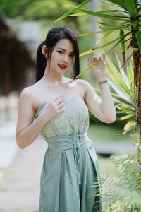 Portrait of young woman standing against trees