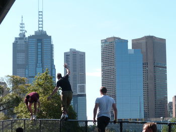 People on modern buildings in city against sky