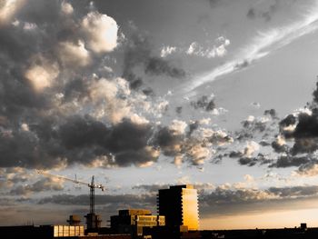 Silhouette of factory against cloudy sky