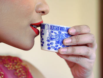 Cropped image of woman having drink in cup