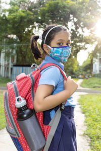 Portrait of a happy indian girl child student in school uniform,nose mask protection going to school