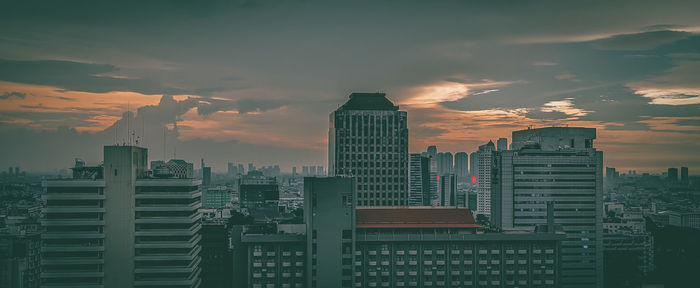 Buildings in city against sky during sunset