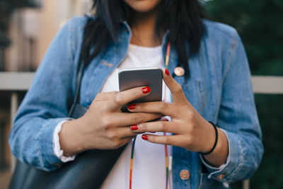 Midsection of teenage girl using smart phone