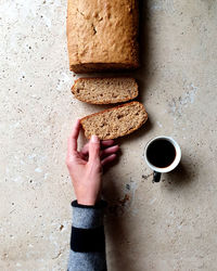 Directly above shot of hand holding coffee cup on table