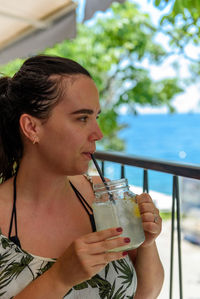 Portrait of girl wearing sundress, drinking lemonade in bar by sea