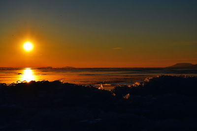 Scenic view of sea against dramatic sky during sunset