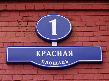 Close-up of road sign against brick wall
