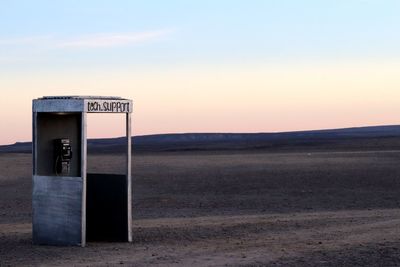 Information sign on field against sky during sunset