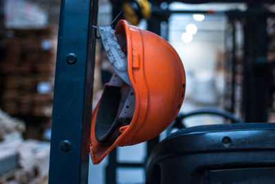 Close-up of orange hardhat hanging on hook in factory