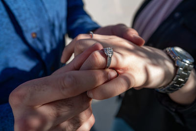 Close-up of man wearing engagement ring to woman