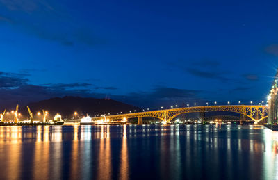 Illuminated bridge over river against sky at night