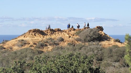 People standing on cliff against sky