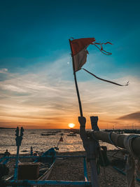 Ship moored on beach against sky during sunset