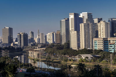 Modern buildings in city against clear sky and river foreground 