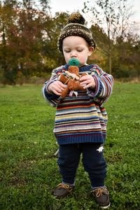 Cute boy holding toy while standing on field