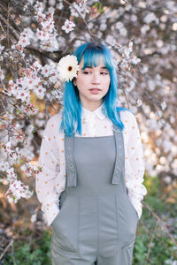 Portrait of a beautiful young woman standing by flowering plants