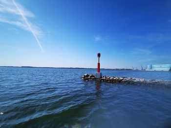 Lighthouse by sea against blue sky