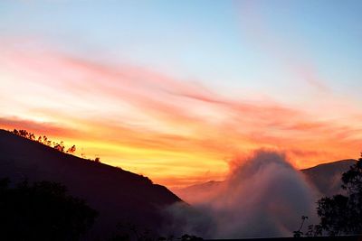 Scenic view of mountains against cloudy sky at sunset