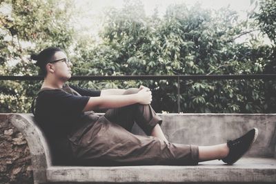 Man sitting on plant against trees