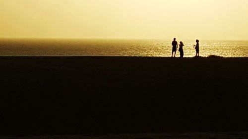 Silhouette of people on beach at sunset